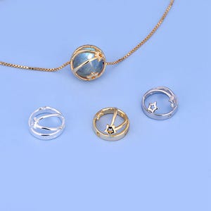 Puede incluir: Un collar de cadena de plata con un colgante de oro que presenta una piedra preciosa redonda azul con estrellas en su interior. Hay tres colgantes adicionales, dos de plata y uno de oro, con recortes en forma de estrella.