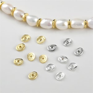 Könnte beinhalten: Eine Sammlung ovaler Perlenkappen in Gold und Silber mit einem dekorativen Design. Die Perlenkappen haben ein Loch in der Mitte zum Aufziehen.