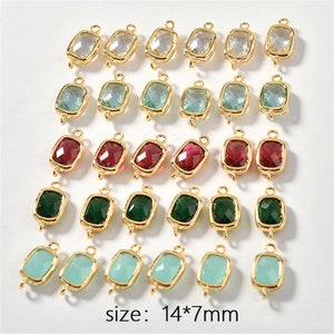 May include: Twenty-four gold-toned metal charms with faceted glass inserts. The charms are in various colors, including clear, light blue, green, red, and dark green. Each charm has two loops for attaching to jewelry or other crafts. The charms are arranged in four rows of six. The text "size: 14*7mm" is printed below the charms.