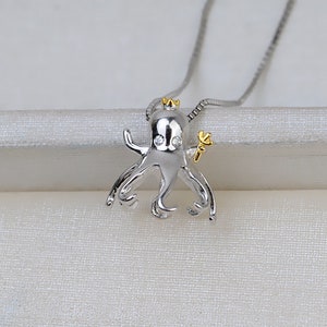 Peut inclure: Collier en argent avec un petit pendentif en forme de pieuvre portant une couronne et tenant une fleur. La pieuvre a des yeux en pierres précieuses transparentes.
