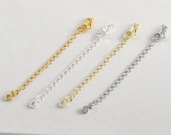 May include: Three extender chains in gold, silver, and rhodium plating, each featuring a clear crystal at the end and a lobster clasp.
