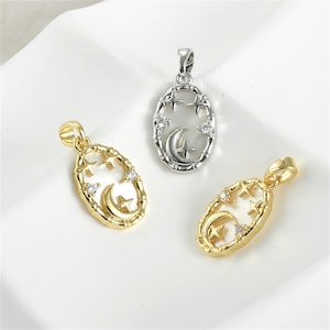 May include: Three oval-shaped pendants with celestial designs. Two are gold-toned, and one is silver-toned. Each pendant features a crescent moon, stars, and clear accent stones within a decorative frame. The pendants are displayed on a white surface.