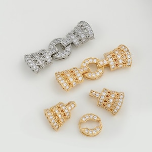 May include: Two silver and two gold tone metal clasps with clear crystal embellishments. The clasps are designed to be used as jewellery connectors.