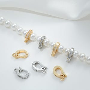 May include: A set of six gold and silver clasps with clear crystal accents. The clasps are designed for jewelry making and feature a hook and loop closure.