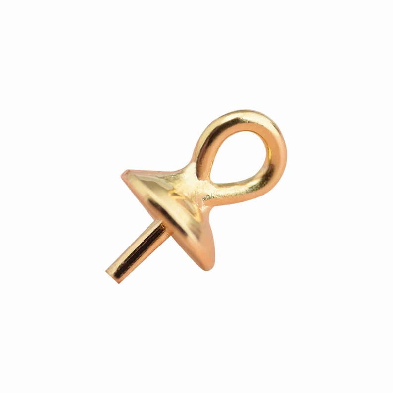 Puede incluir: Un enganche para joyer&iacute;a de metal en tono dorado que presenta un peque&ntilde;o lazo circular en la parte superior y una base plana y ensanchada con un pasador corto y recto que se extiende hacia abajo, dise&ntilde;ado para colgar dijes o colgantes.
