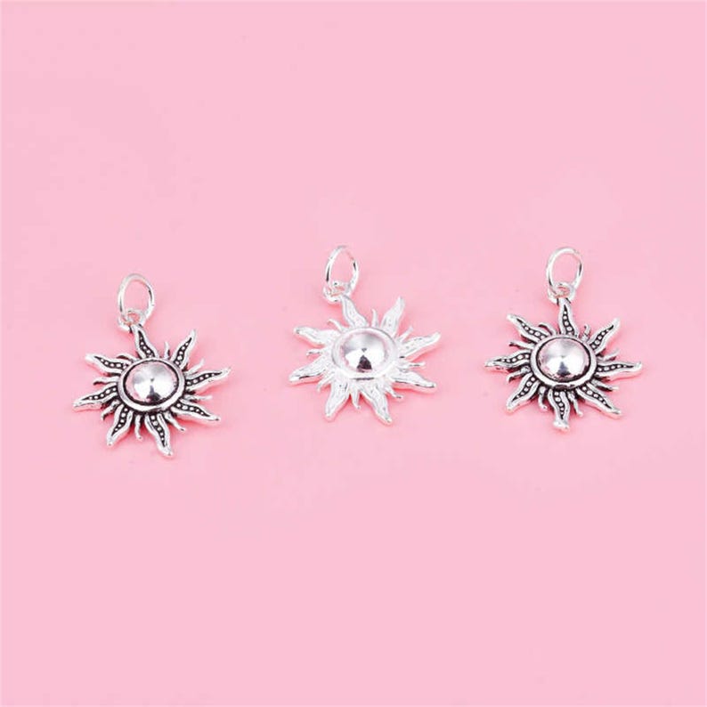 Puede incluir: Tres colgantes de sol de plata con un dise&ntilde;o detallado. Cada colgante presenta un centro redondo con una superficie texturizada en relieve y rayos que irradian.