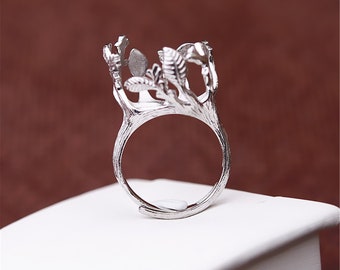 May include: Silver ring with a tree branch design. The ring is open and adjustable. The ring is made of metal and has a natural finish.