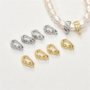 May include: A set of eight gold and silver metal clasps for jewelry making. The clasps are designed with a decorative, geometric pattern.