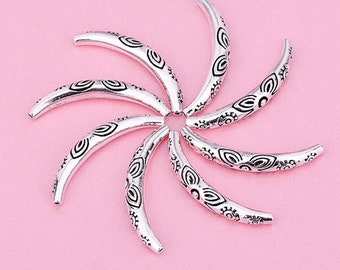 May include: A set of eight silver-toned metal bead caps with intricate floral designs. The bead caps are shaped like half-circles and have a smooth, polished finish.