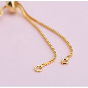May include: A gold chain bracelet with a sliding clasp. The chain is made of small, round links.