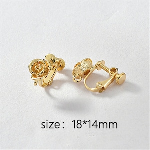 May include: A pair of gold-tone clip-on earrings featuring a rose design. The earrings measure 18mm by 14mm.