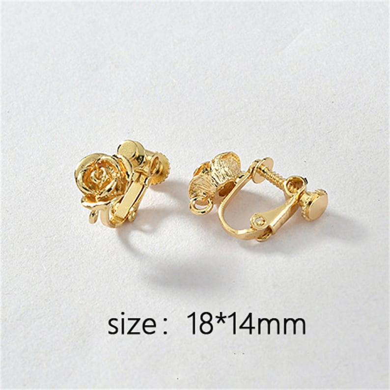 May include: A pair of gold-tone clip-on earrings featuring a rose design. The earrings measure 18mm by 14mm.