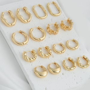 May include: Set of 10 gold hoop earrings in various styles and sizes. The earrings are arranged on a white surface.