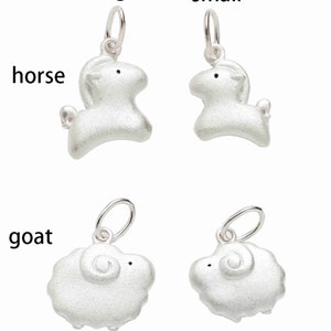 May include: Two silver charms, one depicting a horse and the other a goat. The horse charm is available in two sizes, labelled "large" and "small".