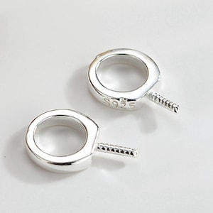 Könnte beinhalten: Zwei silberne Sprungringe mit einem Gewindebolzen, jeder Ring ist mit "S925" für Sterlingsilber gekennzeichnet.