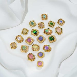 May include: Assortment of 18 gold-tone brooches with iridescent and green gemstone accents. Each brooch features a unique design with a variety of shapes and sizes.