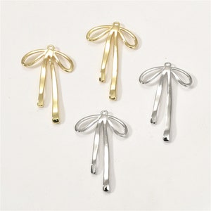 May include: Four gold and silver bow-shaped metal charms. The charms are designed to be used for jewelry making.