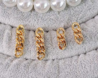 May include: Four gold-colored chain link charms of varying sizes are displayed on a gray, textured surface. The charms are arranged in a vertical line. A strand of white pearls is visible in the background.
