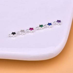 May include: Five silver star-shaped charms with different colored gemstones. The charms have a loop at the top for attaching to jewelry.