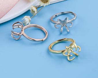 Op de afbeelding: Drie zilveren ringen met een decoratief bloemendesign. De ringen liggen op een blauwe ondergrond.