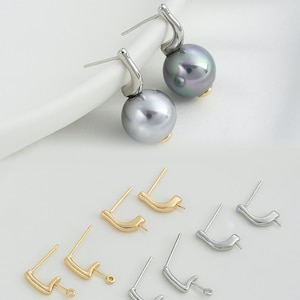 May include: A pair of silver earrings with a black pearl dangle. The earrings are shown with a variety of earring findings in gold and silver.