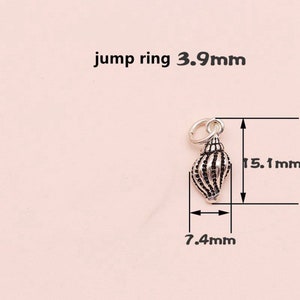K&ouml;nnte beinhalten: Silberner Muschel-Anh&auml;nger mit detailliertem Design. Der Anh&auml;nger ist 15,1 mm hoch und 7,4 mm breit.