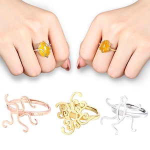 Peut inclure: Quatre bagues en or avec des designs différents. Deux bagues présentent une pierre jaune, une bague a un motif floral et une bague a un design plus abstrait.