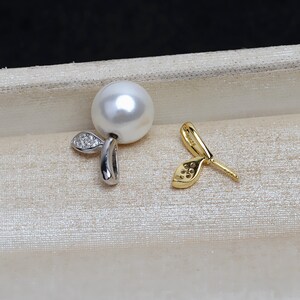 Puede incluir: Un par de pendientes de perlas. Un pendiente presenta una perla blanca grande con un acento plateado y pequeñas piedras transparentes. El otro pendiente es de color dorado con un diseño en forma de hoja y pequeñas piedras transparentes.