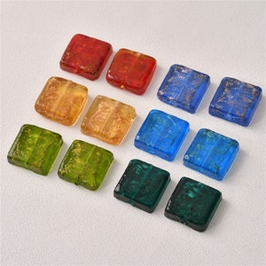Può includere: Assortimento di perline quadrate di vetro con pagliuzze dorate in vari colori, tra cui rosso, arancio, giallo, verde, blu e verde acqua.