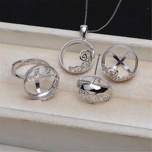 May include: A silver jewelry set with a pendant, earrings, and a ring. Each piece features a circular design with a delicate, swirling pattern.