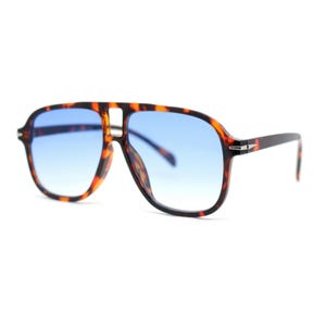 May include: Aviator-style sunglasses with a tortoiseshell frame and gradient blue lenses. The sunglasses have a thick brow bar and temples, and a silver accent on the temples. The lenses transition from a darker blue at the top to a lighter blue at the bottom.