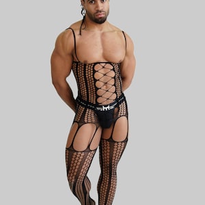 May include: Black fishnet bodysuit with a lace-up front and suspender straps. The bodysuit features a dot pattern and cut-out details on the legs. A black thong is visible under the bodysuit.
