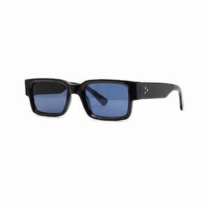 May include: Black rectangular sunglasses with blue lenses. The sunglasses have a thick, solid frame with a subtle design on the temples. The lenses are a deep blue color, and the overall style is modern and sleek.