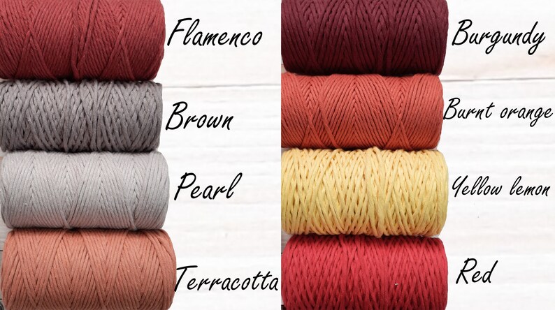 May include: Four spools of cotton rope in various colours, including terracotta, pearl, brown, and flamenco. The spools are arranged in two stacks of two, with the colours alternating. The text "Flamenco", "Brown", "Pearl", "Terracotta", "Burgundy", "Burnt orange", "Yellow lemon", and "Red" is written next to each spool.