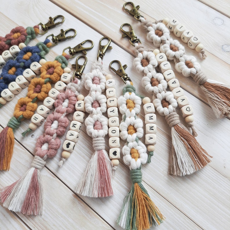 Macrame flower keychains with wooden bead name. Retro gold clasp and soft cotton cord. The whole item is 7" long. The flowers come in several light and dark colors. The wooden beads have letters, numbers, hearts and some special characters.