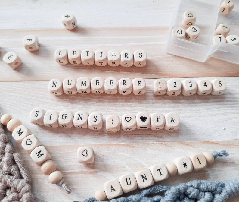 May include: Wooden blocks spelling out the words "LETTERS", "NUMBERS", and "SIGNS". The blocks also include numbers, punctuation marks, and symbols. There are also wooden beads spelling out the words "MOM" and "AUNT".