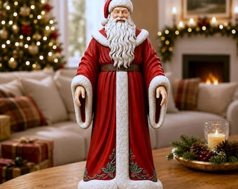 May include: A standing Santa Claus figurine wearing a long, deep red robe with thick white faux fur trim on the collar, cuffs, and hem. The robe features embroidered green holly leaves and red berries at the base. Santa has a long white beard.