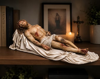 May include: A detailed sculpture of a reclining figure with long hair and a crown of thorns, lying on a draped cloth. The figure has visible wounds on the chest, arms, and legs, rendered in realistic skin tones with subtle shading and texture.