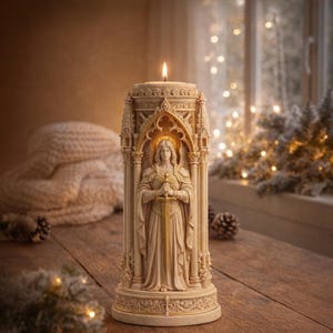 Op de afbeelding: Een beige kaars in een gotisch kathedraalontwerp, met een standbeeld van een vrouw die een zwaard vasthoudt. De kaars is aangestoken, met een warme gloed. De kaars staat op een houten oppervlak.