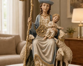 May include: A decorative figurine of a seated figure wearing a blue hat and robe, holding a child and a tall, ornate gold staff. The figure is surrounded by three sheep on a green base, with intricate gold detailing on the clothing and staff.