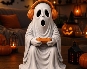 May include: A white ghost figurine wearing orange over-ear headphones and holding an orange video game controller. The ghost has a wide, open-mouthed expression with hollow eyes, and the figure is rendered in a smooth, matte finish.