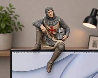 May include: A figurine of a medieval knight wearing a chainmail coif and tunic with a red cross emblem on the chest. The knight is seated, holding a grey metal helmet in one hand, and is dressed in brown greaves and boots over chainmail armor.