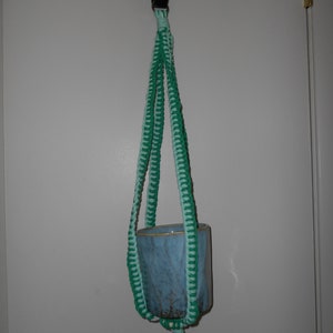 May include: A green and light blue macrame plant hanger with a blue ceramic pot hanging from it.