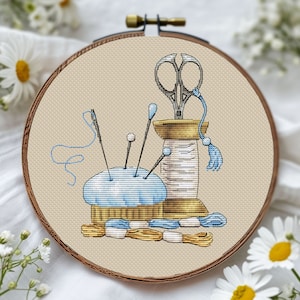 May include: Cross-stitch embroidery in a wooden hoop features sewing tools. A light blue pincushion holds needles and pins. A spool of thread, scissors, and thread skeins in blue and gold complete the design. The background is a light beige fabric.