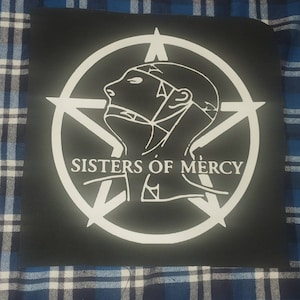 May include: Black and white patch with a circle containing a five-pointed star and a stylized image of a person's head with a rope tied around it. The text "SISTERS OF MERCY" is written below the image.