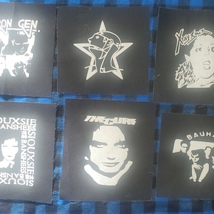 May include: Six black and white fabric patches with band logos. The patches feature the band names "Chron Gen", "Siouxsie Banshees", "The Cure", "X-Ray Spex", "Bauhaus", and a star with a face inside.