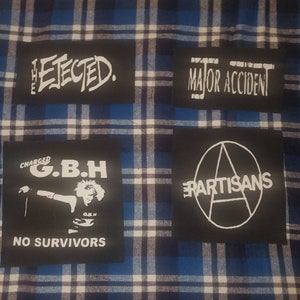 May include: Four black fabric patches with white text and graphics. The patches are sewn onto a blue and white plaid fabric. The patches read "The Elected", "Major Accident", "Charged G.B.H. No Survivors", and "The Partisans".