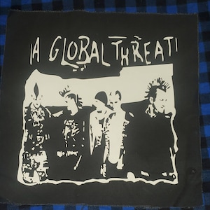 May include: A black and white patch with the text "A Global Threat" and a silhouette of four people.
