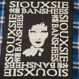 May include: Black and white patch with the text "Siouxsie and the Banshees" repeated around the border. A black and white image of Siouxsie Sioux is in the center of the patch.