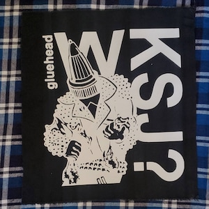 May include: Black and white patch with a cartoon figure wearing a leather jacket and a cone-shaped head. The text "WASK?" and "gluehead" are visible on the patch.